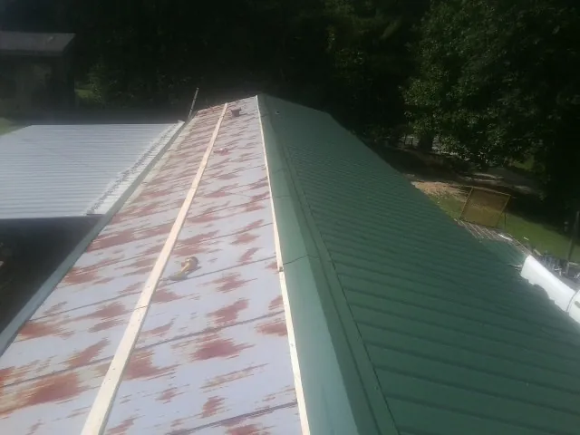 Old rusted panels beside newly installed green metal roofing — Wind Damage Roof Repair by Roofing Brothers in Denton
